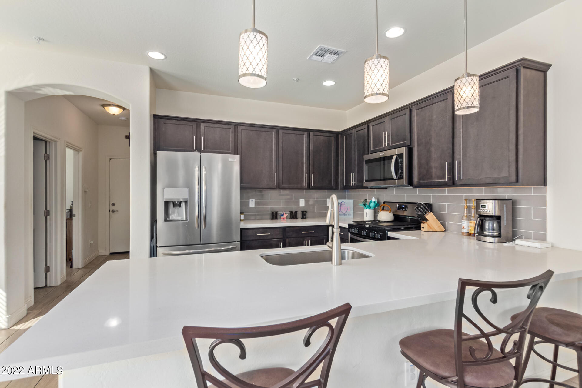 2345 North Alsap Road Buckeye, AZ 85396 - Photo 15 of 50 a kitchen with stainless steel appliances granite countertop a refrigerator a stove a sink a dining table and chairs with wooden floor