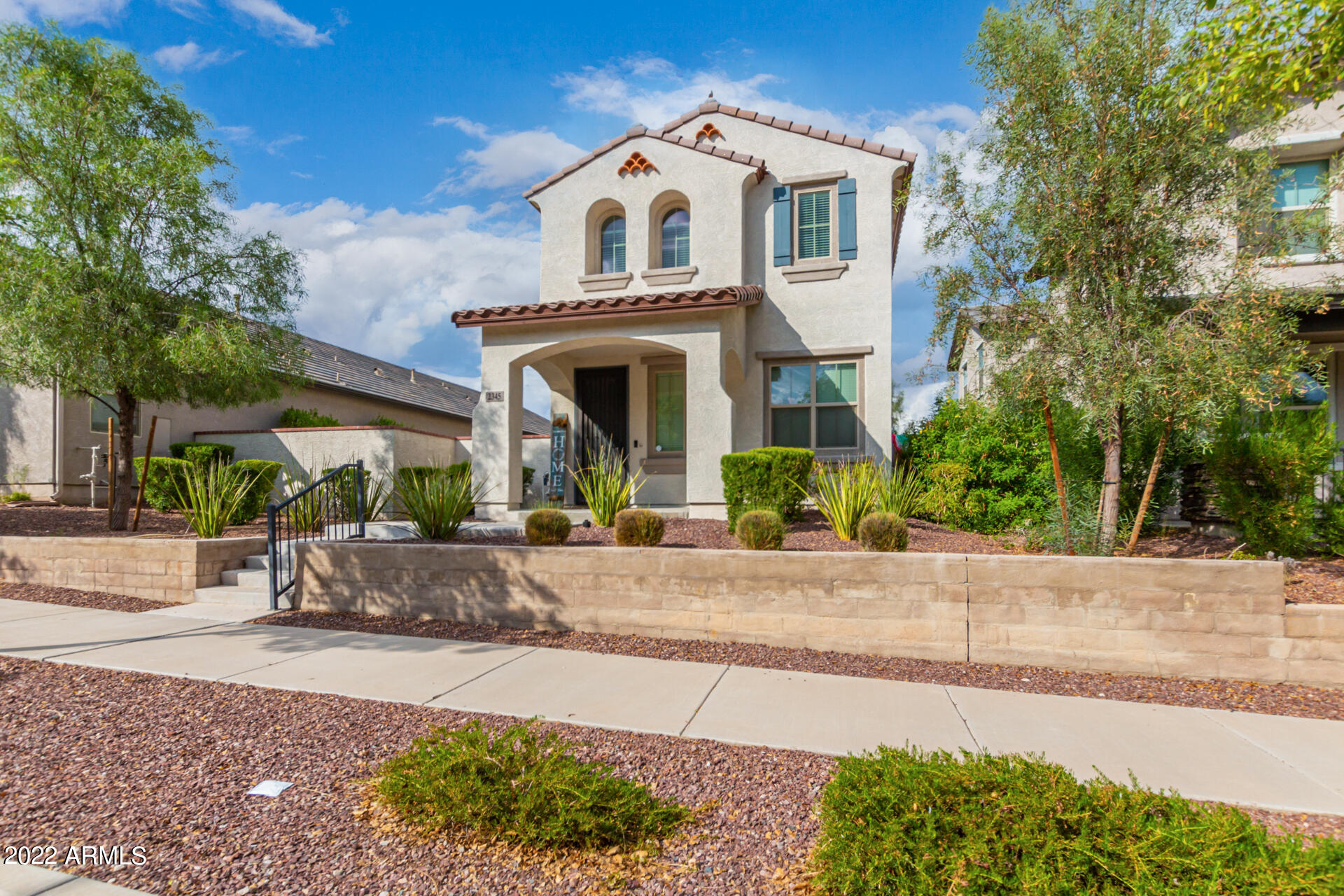 2345 North Alsap Road Buckeye, AZ 85396 - Photo 5 of 50 a view of a white house with large windows and a yard with plants and large trees