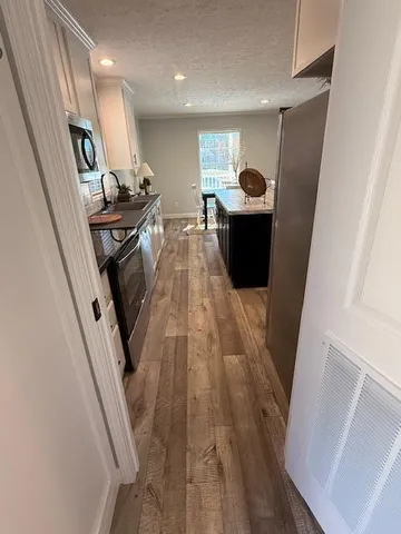 a hallway with a white stove top oven and a dishwasher with wooden floor