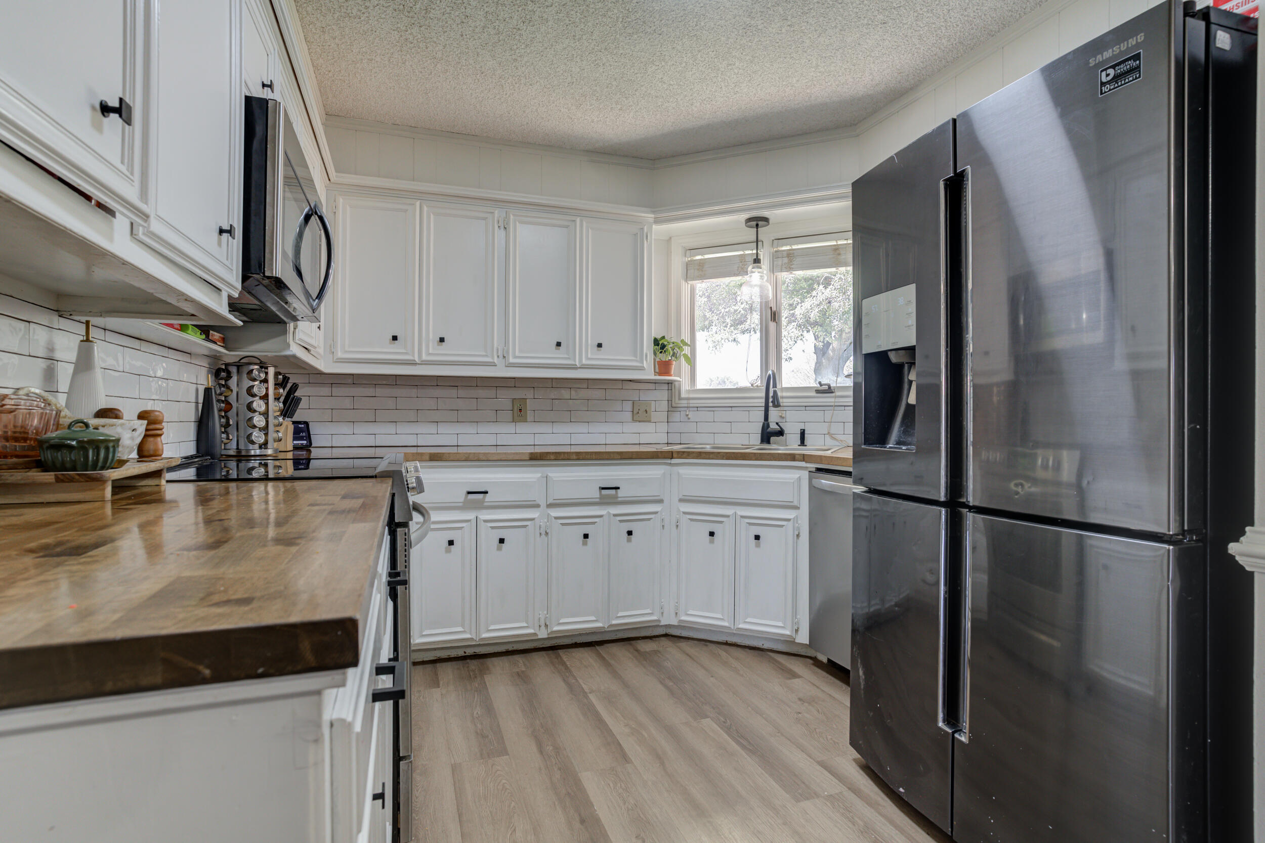 3712 103rd Street Lubbock, TX 79423 - Photo 15 of 43 a kitchen with granite countertop a refrigerator sink and cabinets