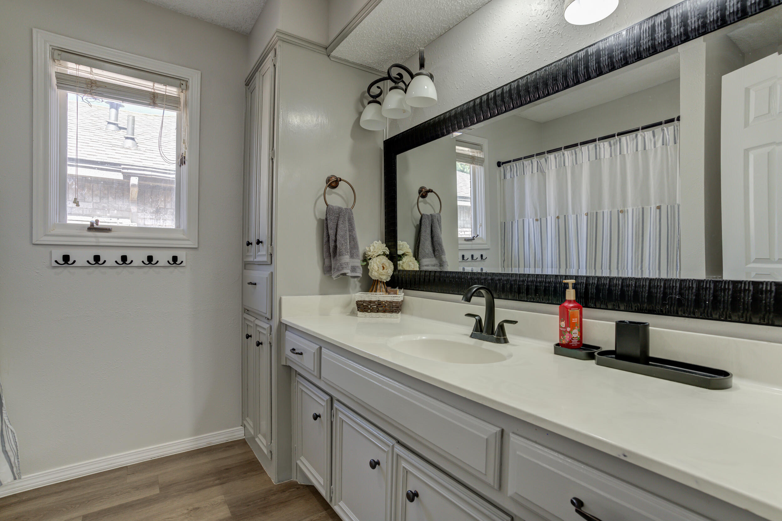 3712 103rd Street Lubbock, TX 79423 - Photo 22 of 43 a bathroom with a double vanity sink a mirror and a window