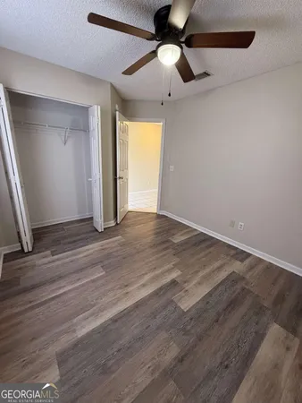 an empty room with wooden floor chandelier fan and windows