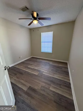 an empty room with wooden floor fan and window