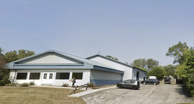 a view of a white house next to a yard with potted plants