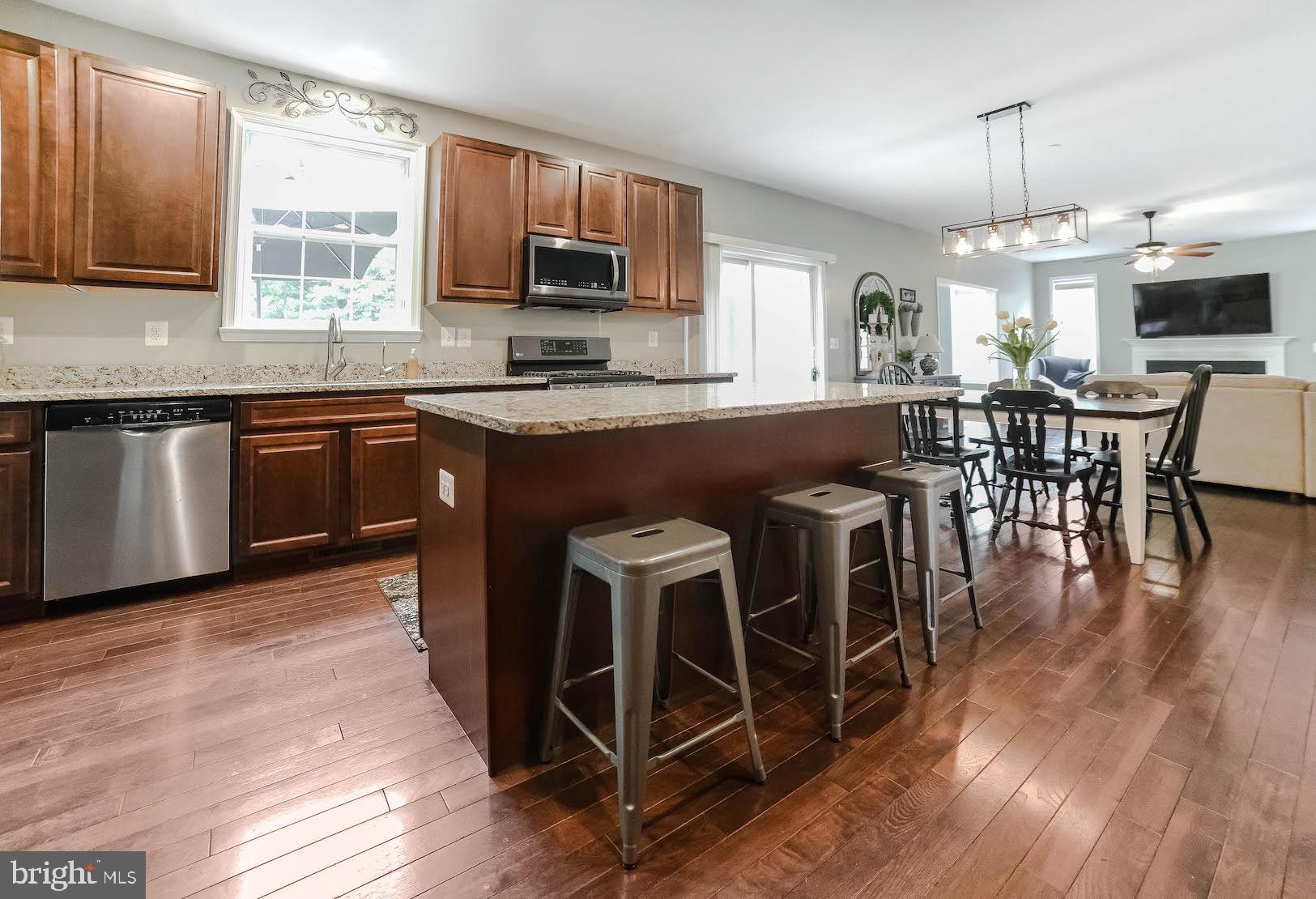 2160 Lowery Road Huntingtown, MD 20639 - Photo 14 of 53 a kitchen with stainless steel appliances granite countertop a stove top oven a sink dishwasher a dining table and chairs with wooden floor