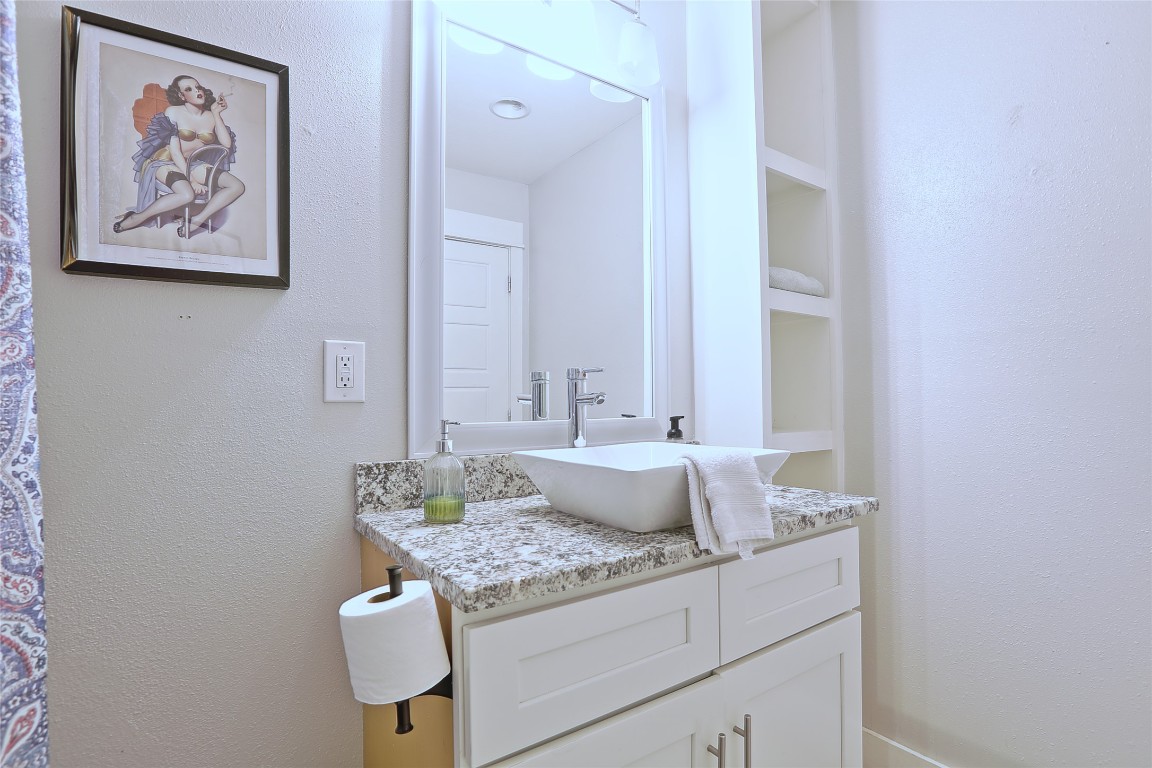 4804 West Wind Trail, Unit 102 Austin, TX 78745 - Photo 21 of 24 a bathroom with a granite countertop sink and a mirror