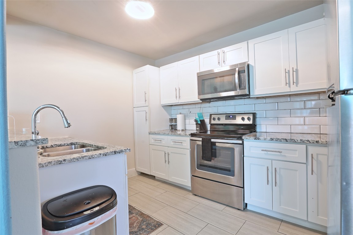 4804 West Wind Trail, Unit 102 Austin, TX 78745 - Photo 7 of 24 a kitchen with stainless steel appliances granite countertop a stove a sink and a microwave