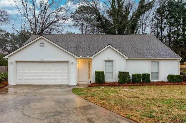 a view of a white house with a yard and large tree