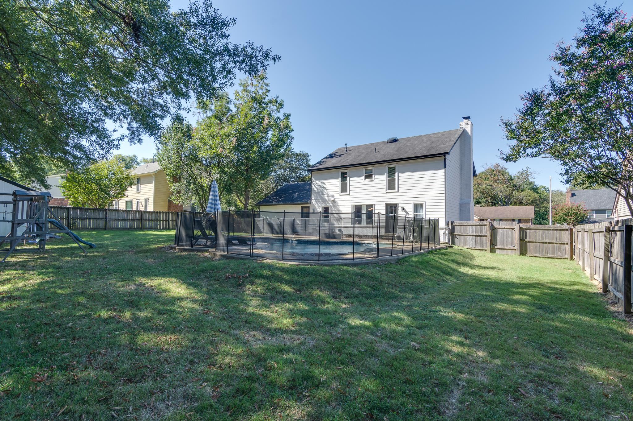 608 King Ridge Cove Collierville, TN 38017 - Photo 28 of 29 Expansive grassy yard with a fenced swimming pool, wood privacy fencing, and mature trees