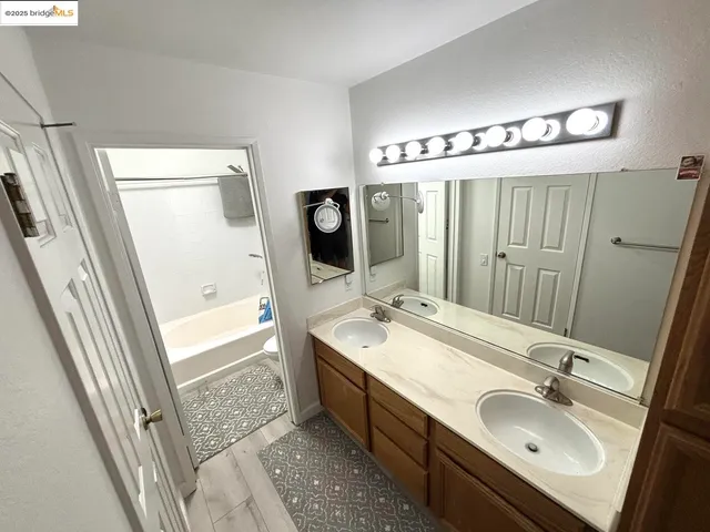 a en suite bathroom with a double vanity sink a mirror and a bathtub