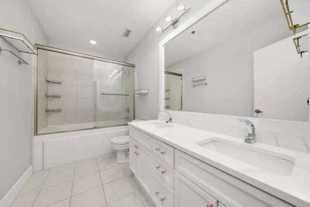 a bathroom with a double vanity sink toilet mirror and shower