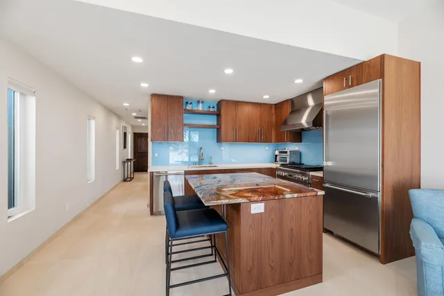 a kitchen with stainless steel appliances granite countertop a refrigerator a sink and a stove