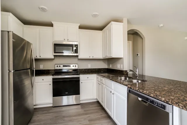 a kitchen with stainless steel appliances granite countertop a stove a refrigerator and a sink