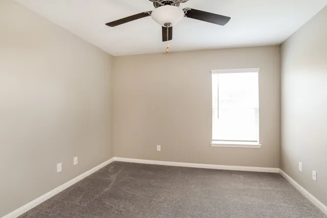 an empty room with a window and a ceiling fan