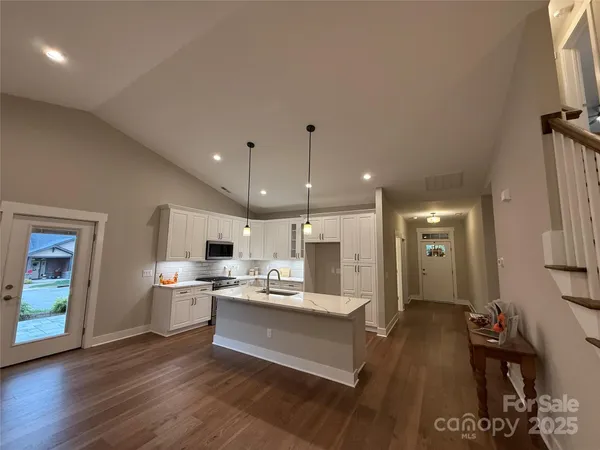 a large white kitchen with a stove a sink dishwasher and a refrigerator with wooden floor