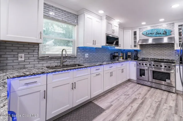 a large kitchen with granite countertop a stove top oven a sink a counter space and cabinets