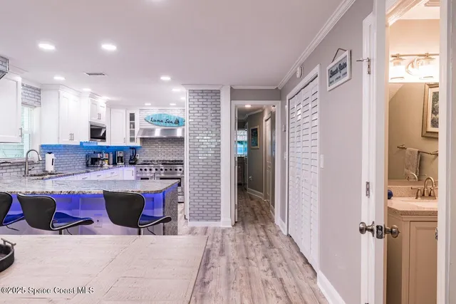 a kitchen with kitchen island a sink a stove a refrigerator and a dining table with wooden floor