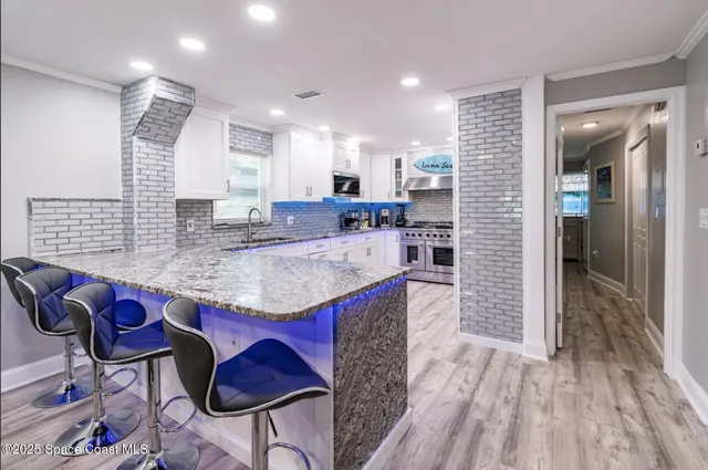 a kitchen with granite countertop kitchen island stainless steel appliances a sink cabinets and wooden floor