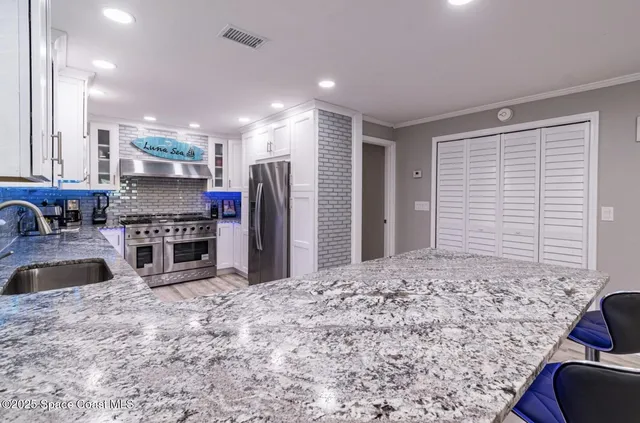 a kitchen with stainless steel appliances kitchen island granite countertop a refrigerator and a sink