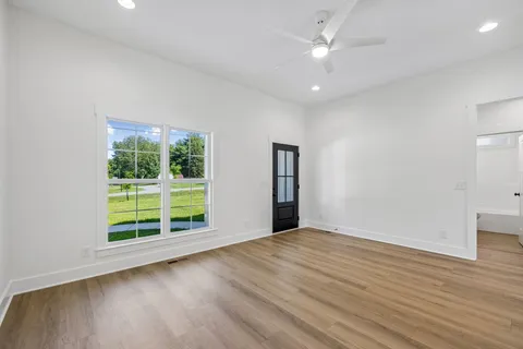 a kitchen with kitchen island granite countertop a refrigerator oven a sink dishwasher and white cabinets with wooden floor