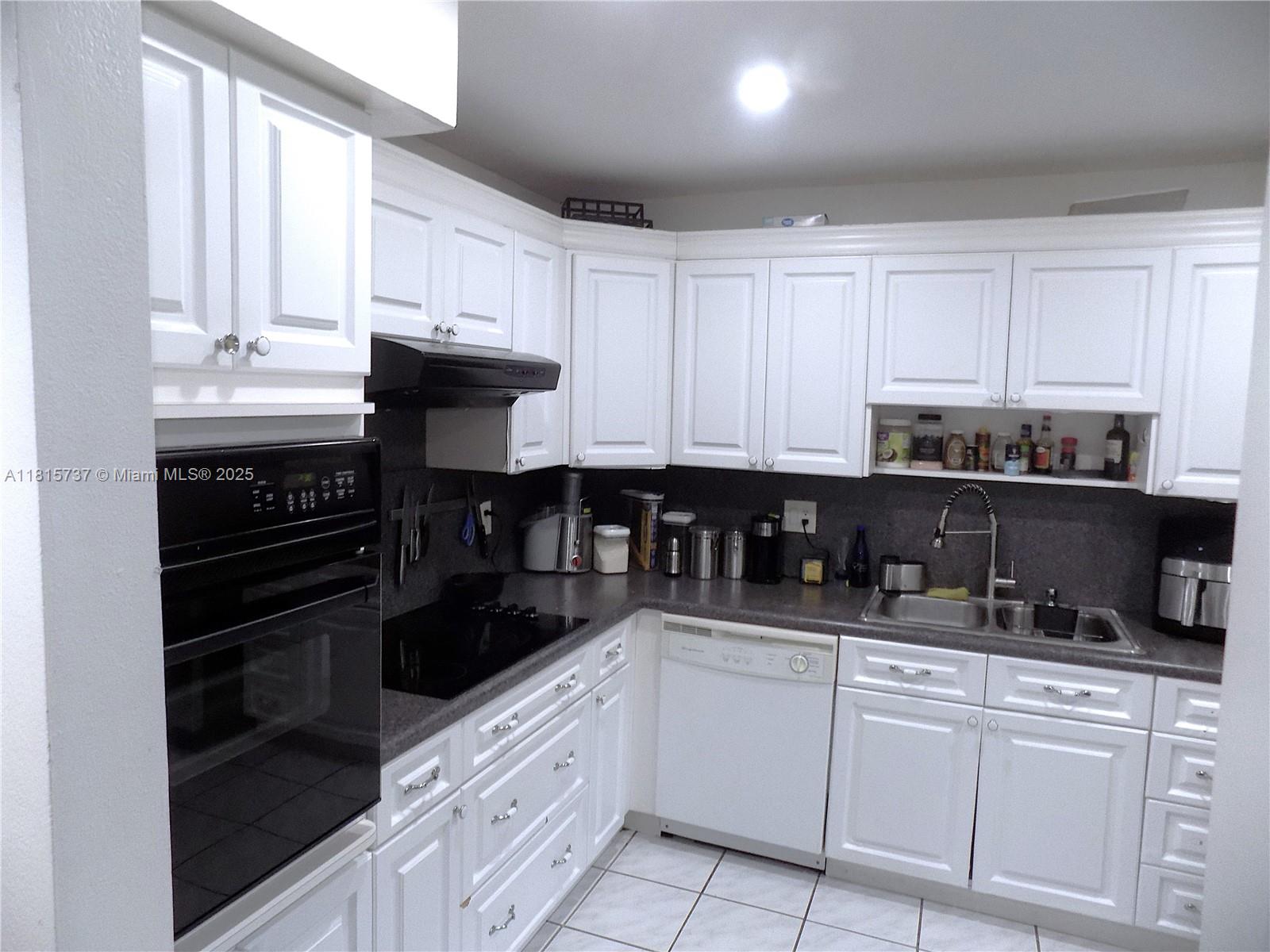 a kitchen with granite countertop white cabinets and stainless steel appliances