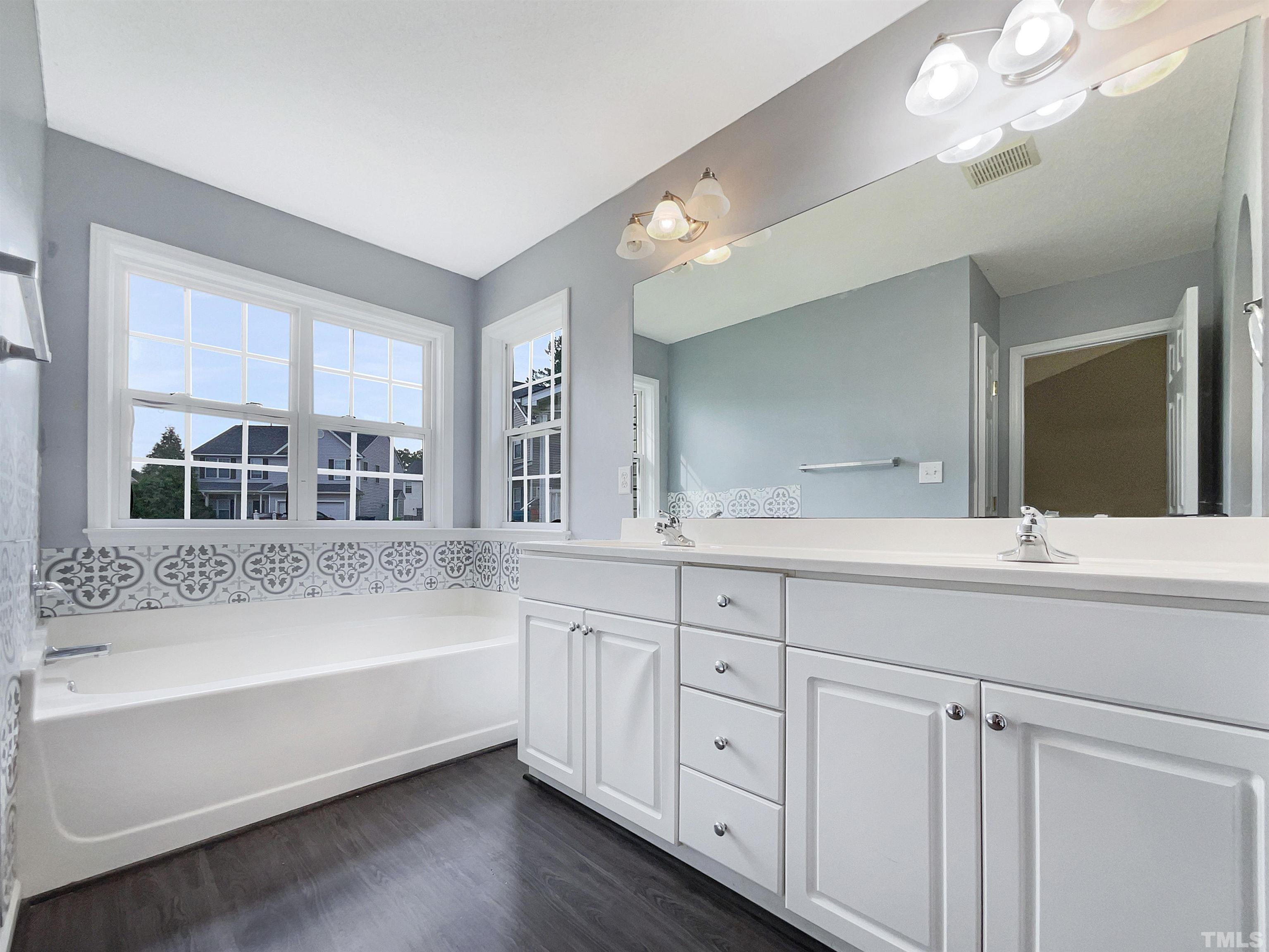 3626 Enduring Freedom Drive Raleigh, NC 27610 - Photo 4 of 17 a bathroom with a tub a double vanity sink and a large mirror