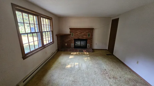 a view of an empty room with a fireplace and a window