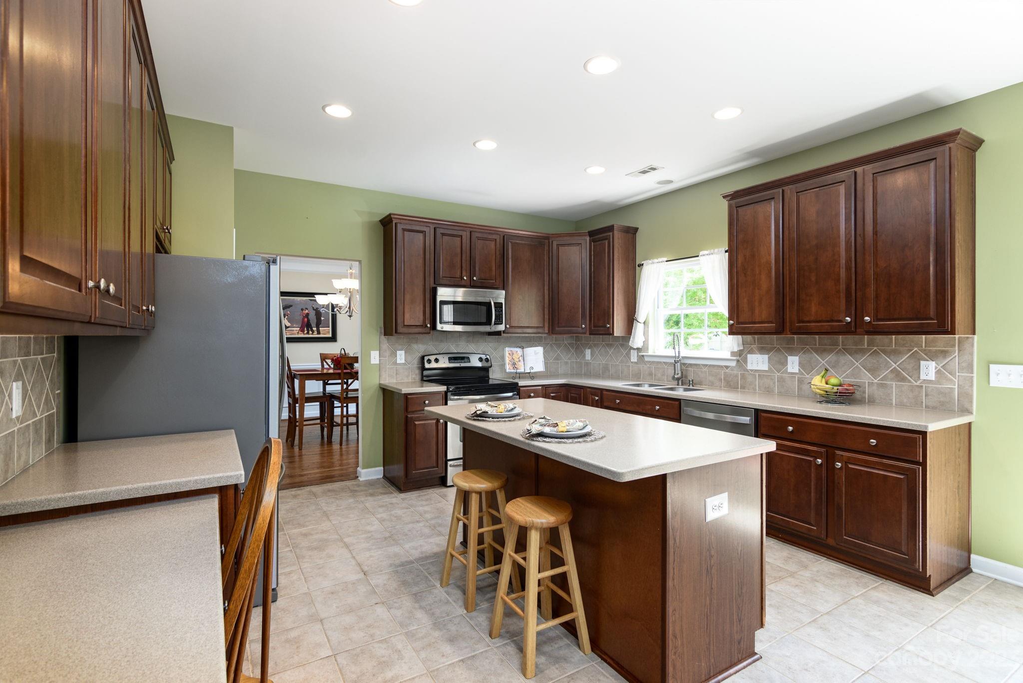 582 Evening Mist Drive Fort Mill, SC 29708 - Photo 10 of 31 a kitchen with stainless steel appliances granite countertop a stove top oven a sink dishwasher a refrigerator and a dining table with wooden cabinet