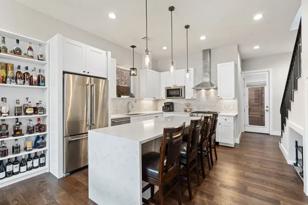 a kitchen with stainless steel appliances a refrigerator a stove a sink and a dining table with wooden floor