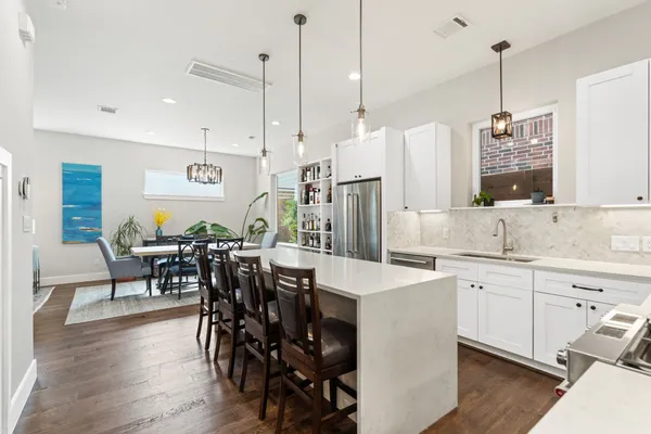 a kitchen with stainless steel appliances a table chairs sink and wooden floor