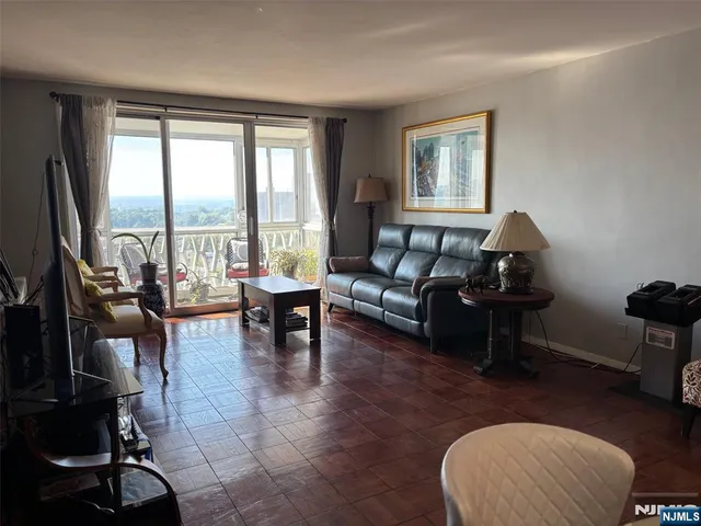 a living room with furniture floor to ceiling window and a flat screen tv
