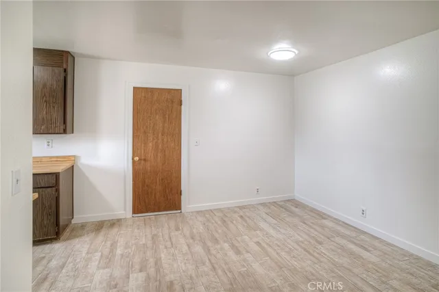 a view of an empty room with wooden floor and a fireplace