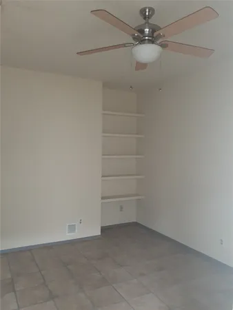 an empty room with a ceiling fan and carpet