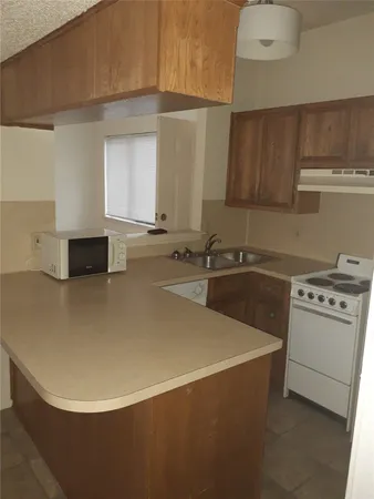 a view of a kitchen with a sink dishwasher stove and cabinets