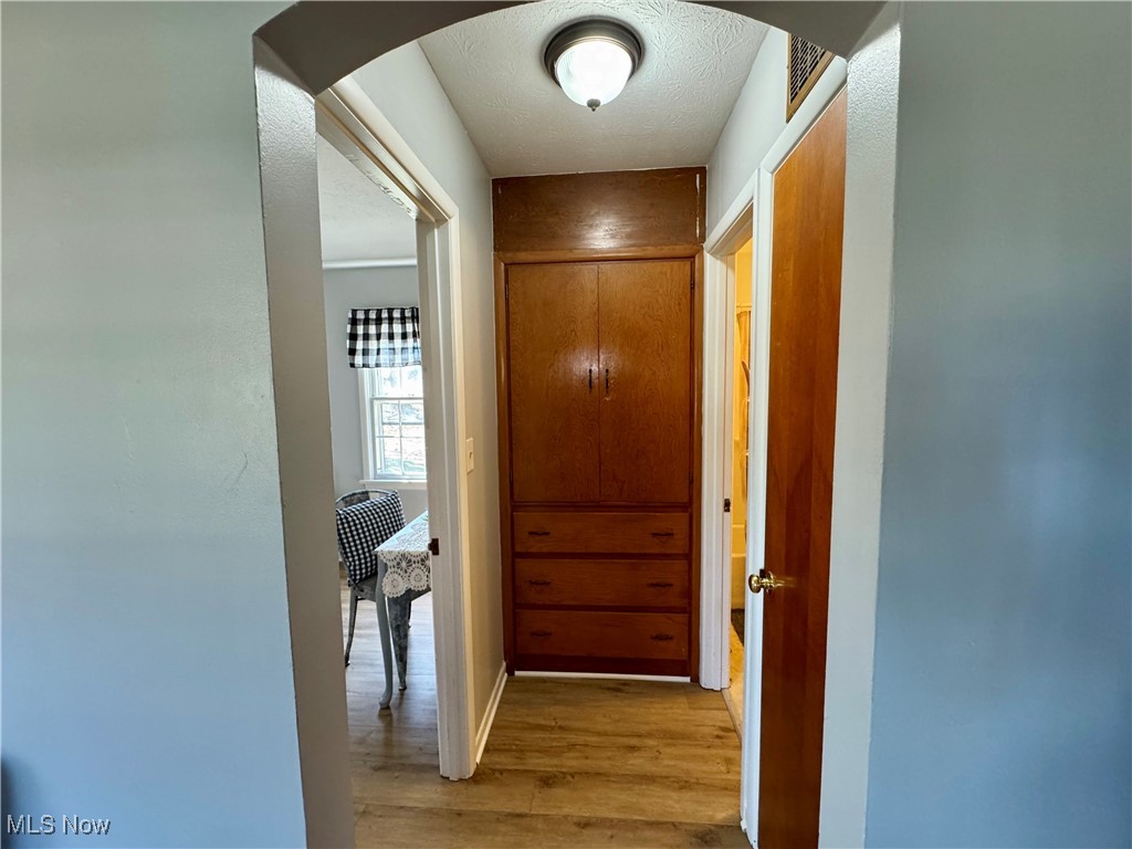 201 West Main Road Conneaut, OH 44030 - Photo 15 of 29 Hallway with a textured ceiling, baseboards, arched walkways, and light wood-style floors