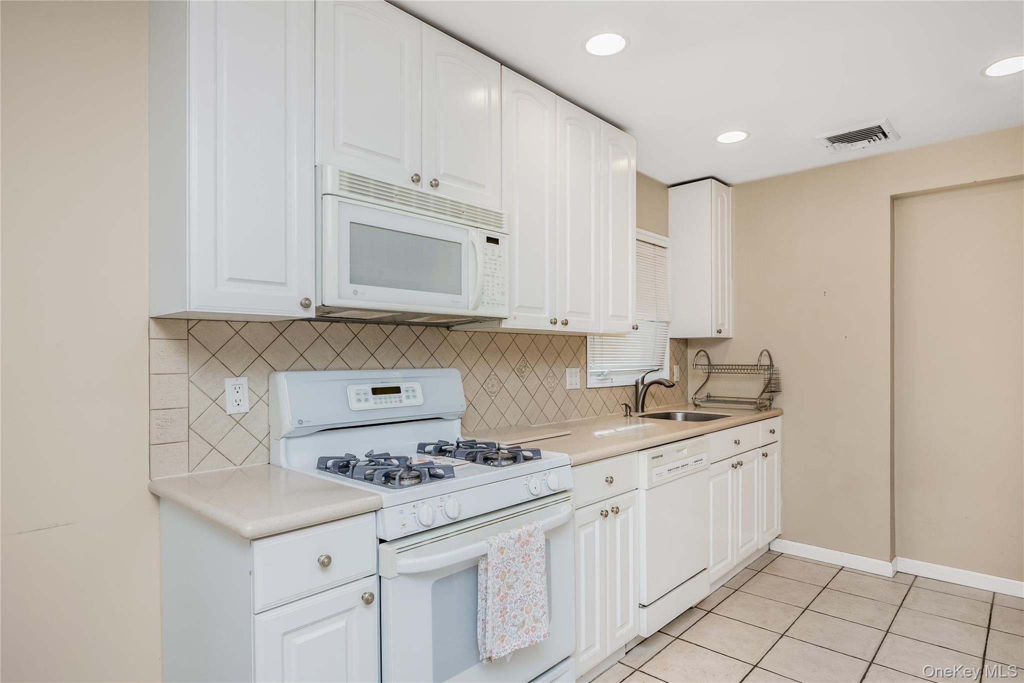 29 Randy Lane Plainview, NY 11803 - Photo 20 of 38 Eat in Kitchen featuring white cabinetry, tile backsplash, stainless steel sink, and recessed lighting