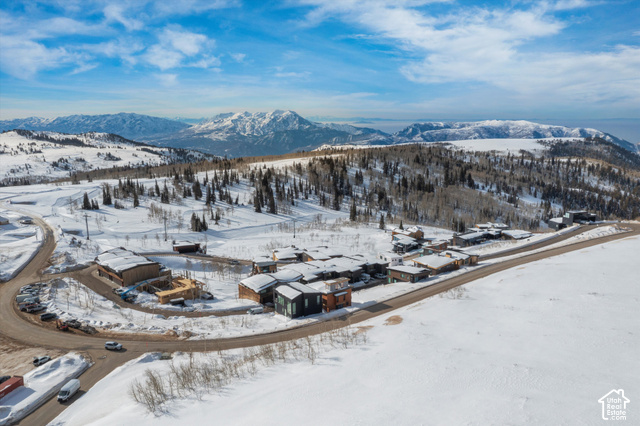 8456 Copper Crest Road, Unit 148 Eden, UT 84310 - Photo 30 of 34 Snow-covered landscape featuring a development of contemporary residences, mountain terrain, and a winding paved road