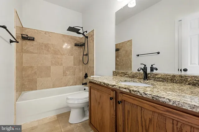 a bathroom with a granite countertop sink a toilet and bathtub