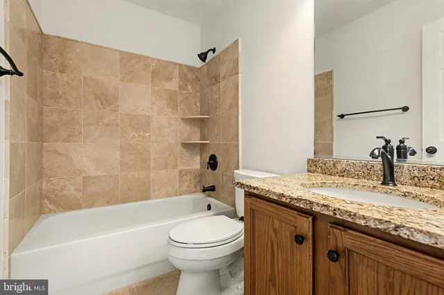 a bathroom with a granite countertop sink a toilet and bathtub
