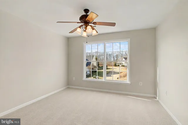 an empty room with window and ceiling fan