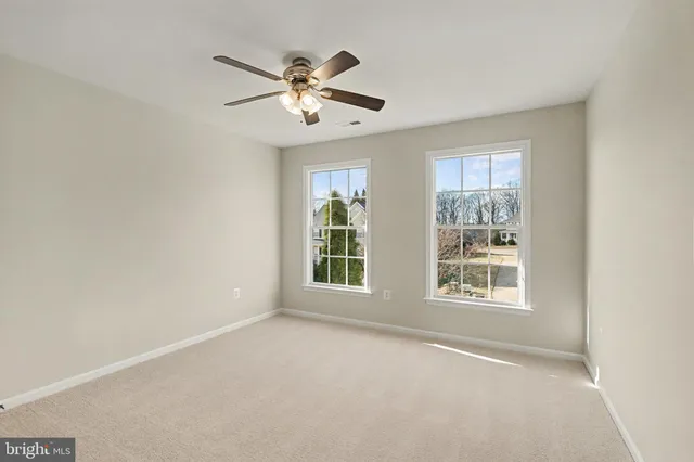 an empty room with windows and fan