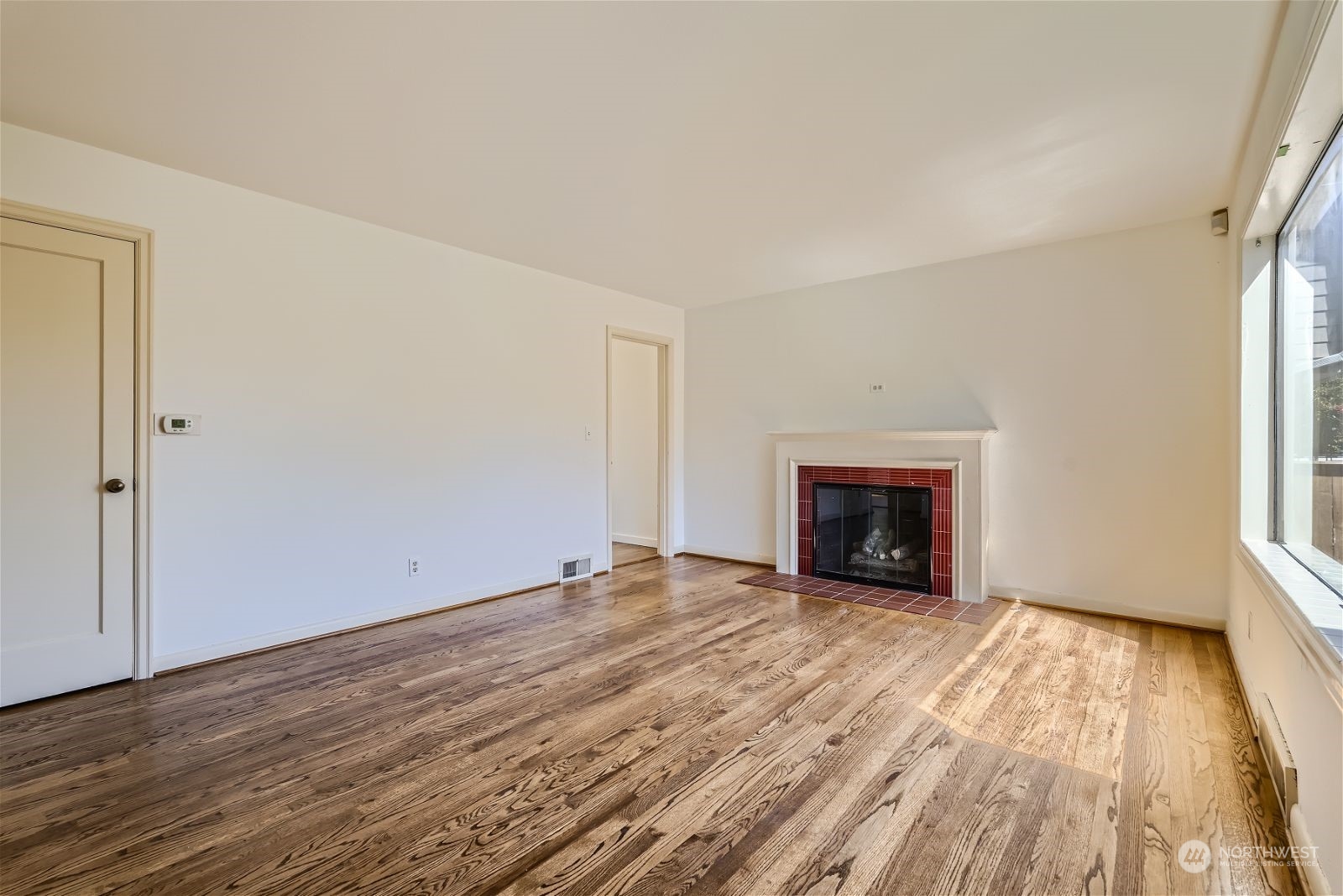 730 North 67th Street Seattle, WA 98103 - Photo 27 of 37 a view of an empty room with wooden floor fireplace and a window