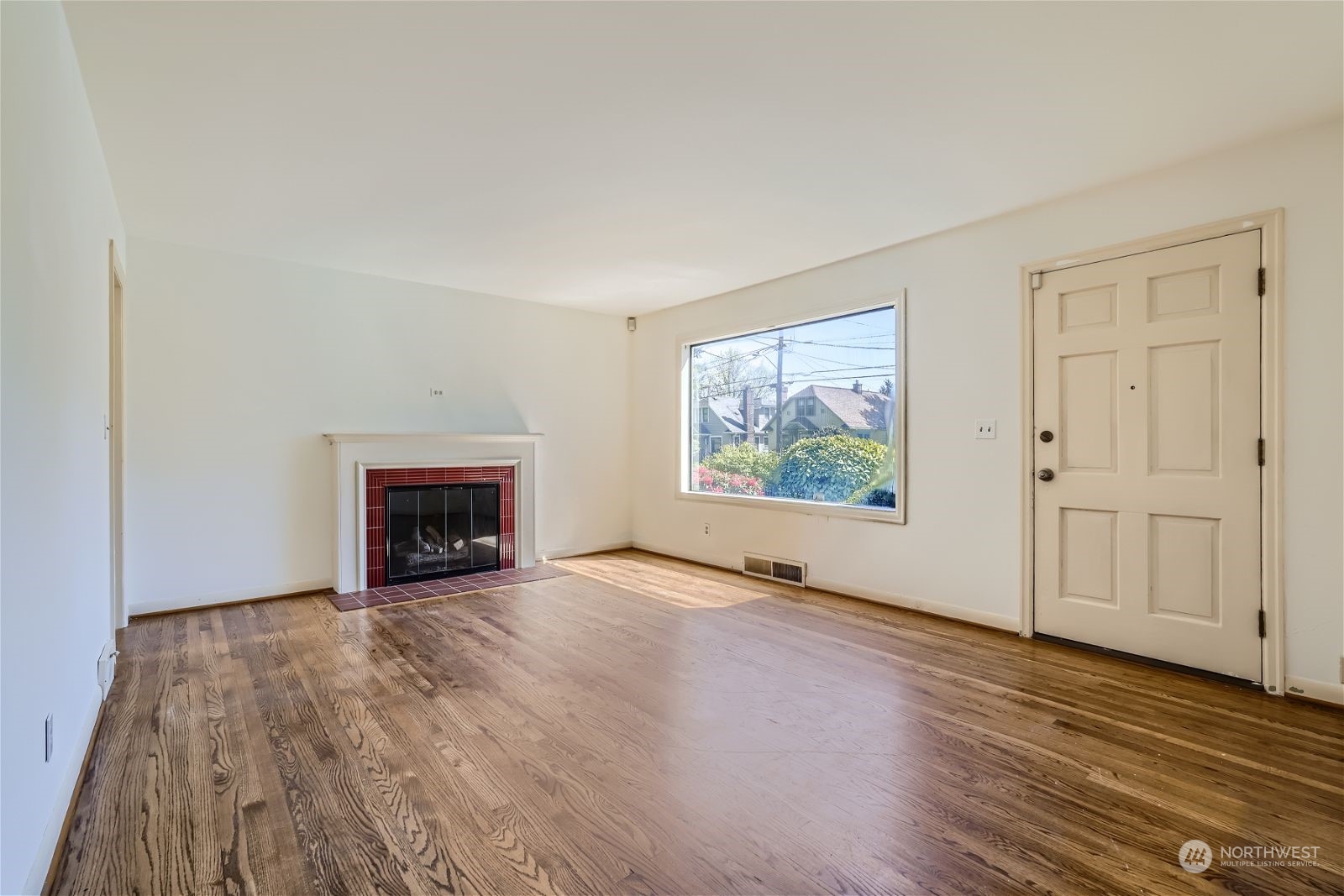 730 North 67th Street Seattle, WA 98103 - Photo 28 of 37 a view of an empty room with wooden floor fireplace and a window