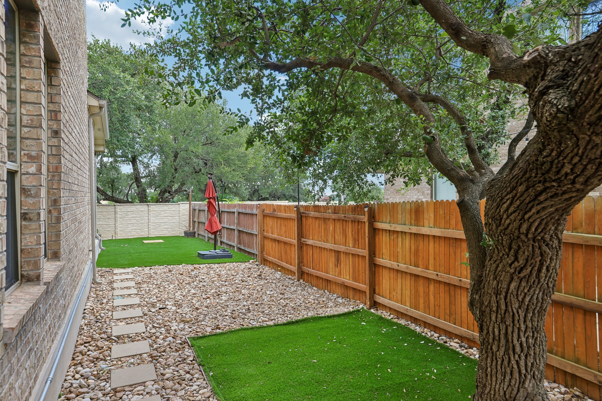 1924 Granite Springs Road Leander, TX 78641 - Photo 33 of 36 A private yard features pavers, a wooden fence, and mature trees, perfect for outdoor enjoyment.