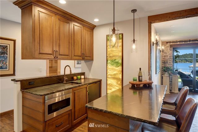 a kitchen with a stove a refrigerator a sink a dining table and chairs with wooden floor