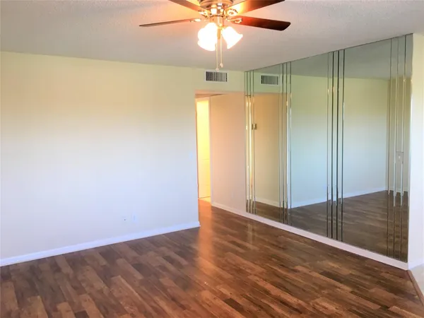 an empty room with wooden floor fan and windows