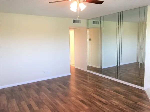 an empty room with wooden floor fan and window