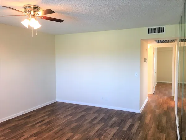 a view of a room with wooden floor and a ceiling fan