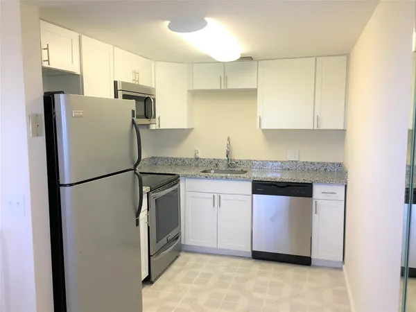 a kitchen with granite countertop a refrigerator sink and cabinets