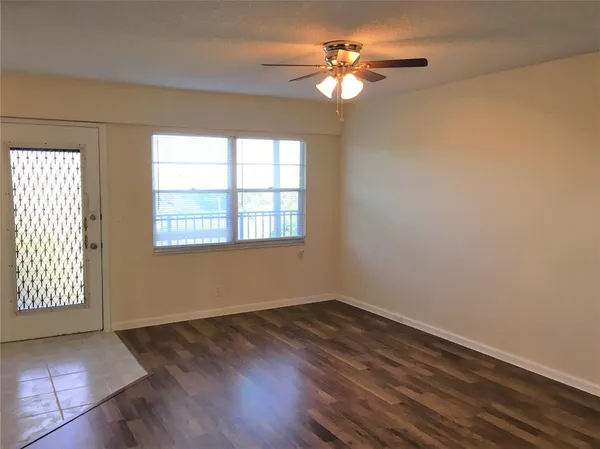 an empty room with wooden floor chandelier fan and windows